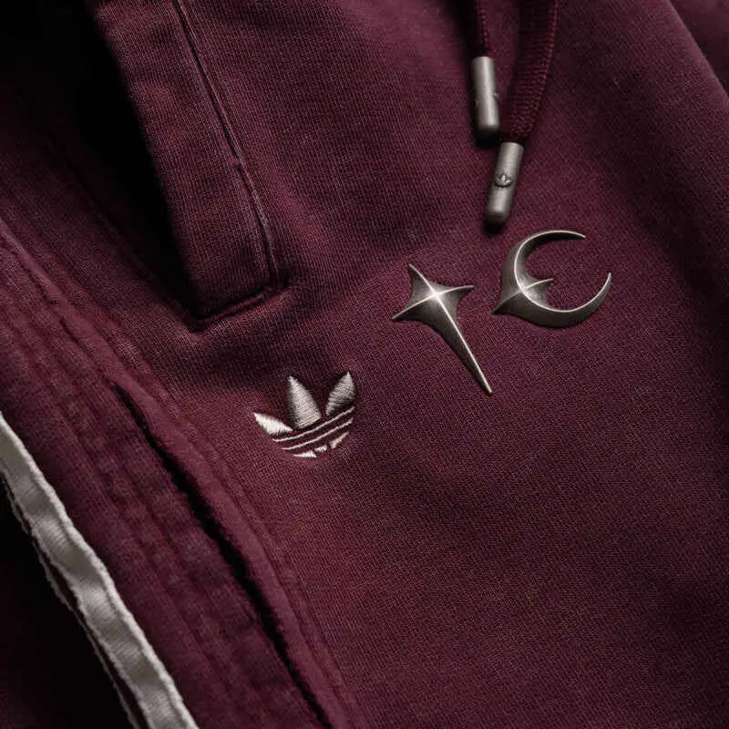 Maroon adidas hoodie with silver embroidered logo and metallic star and crescent pin accents for casual wear