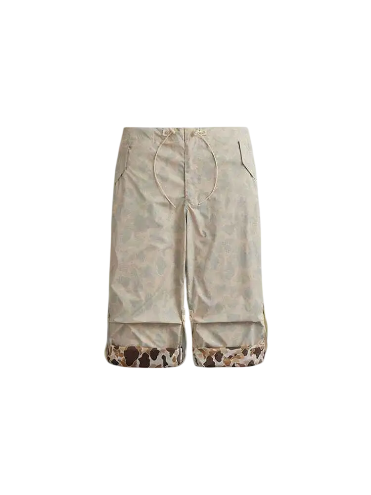 Beige apron with subtle pattern and cow print hem paired with alpha industries lightweight parachute pants limestone frogskin camo