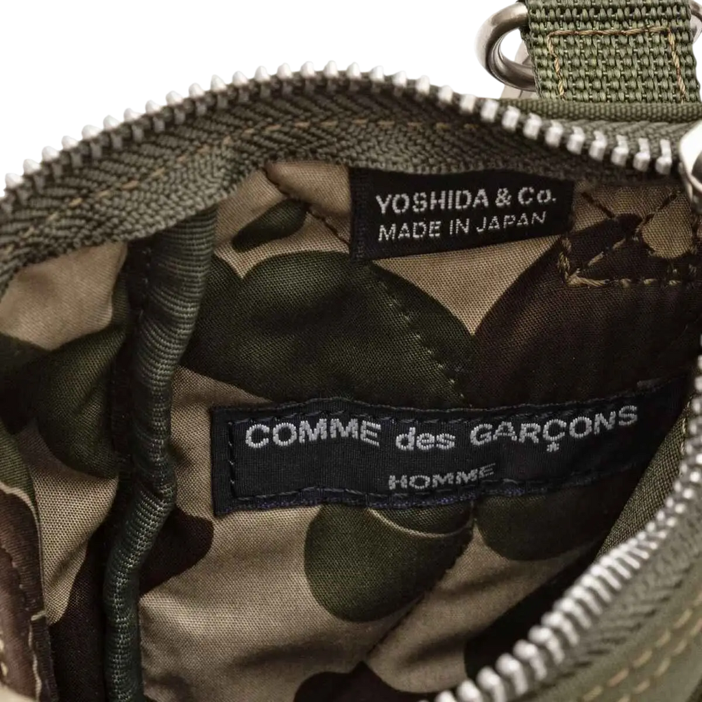 Inside view of camouflage-patterned interior lining in olive green and brown of comme des garçons x porter yoshida shoulder bag