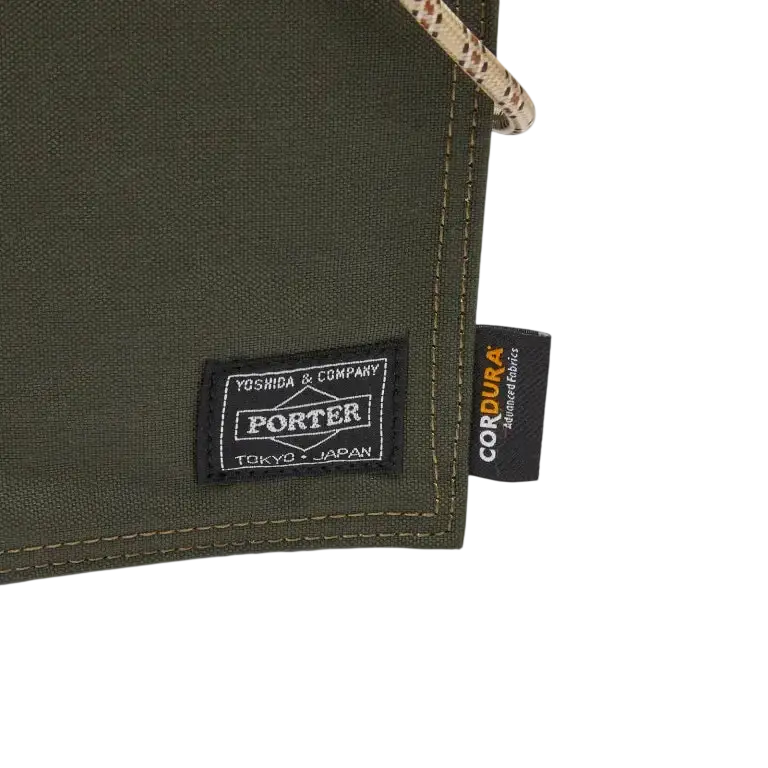 Olive green porter canvas sling pouch with black woven label and cordura fabric tag by comme des garcons x porter