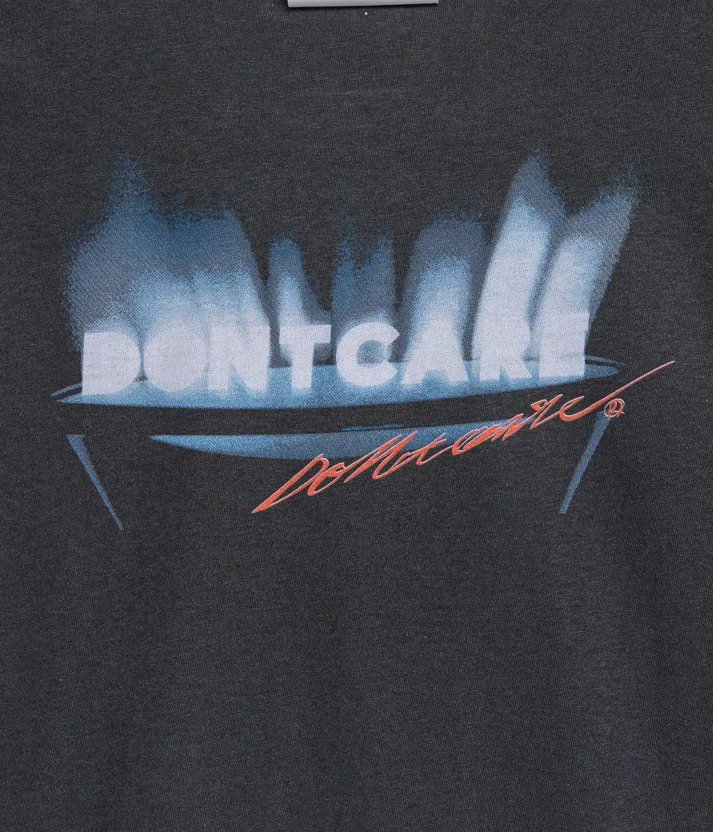 Black cotton t-shirt featuring bold white dontcare text above blue flames with an orange cursive signature below