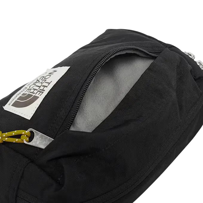 Black north face berkley lumbar bag with zipper opening showing gray interior lining and yellow cord pull