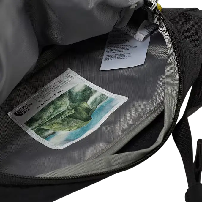 Gray north face berkley lumbar bag interior with printed waterfall label in black and mineral gold colors