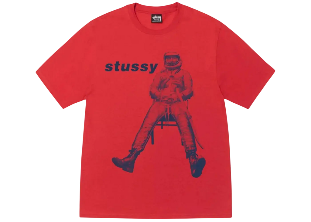 A vibrant red Stussy astronaut tee with a bold blue graphic of an astronaut seated on a chair