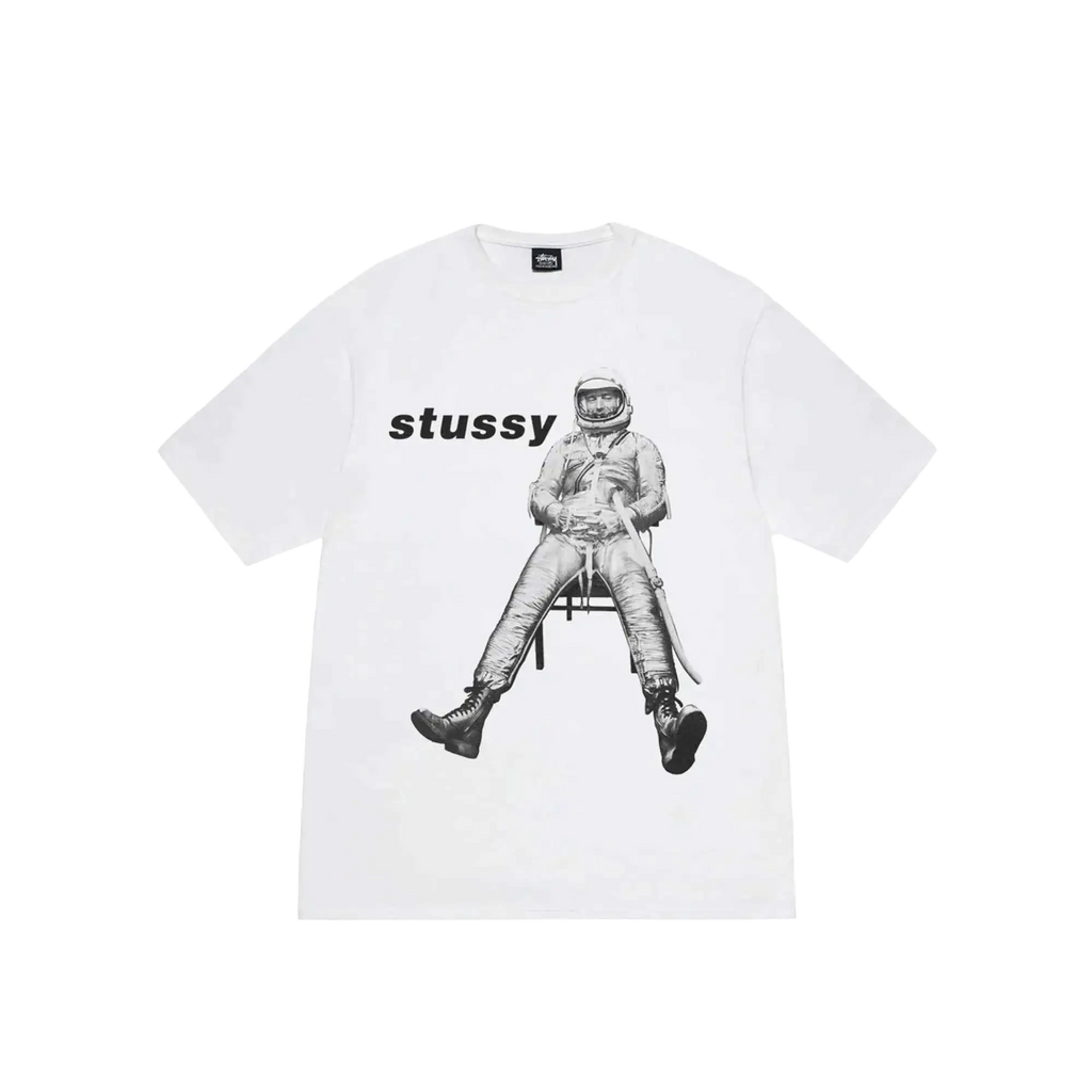 White Stussy astronaut tee featuring a black and white graphic of an astronaut seated on a chair on the front