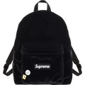 Black velvet supreme backpack with white logo patch and decorative pins showcasing front design