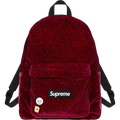 A red velvet supreme backpack with subtle leopard print and decorative pins showcasing the brand logo patch