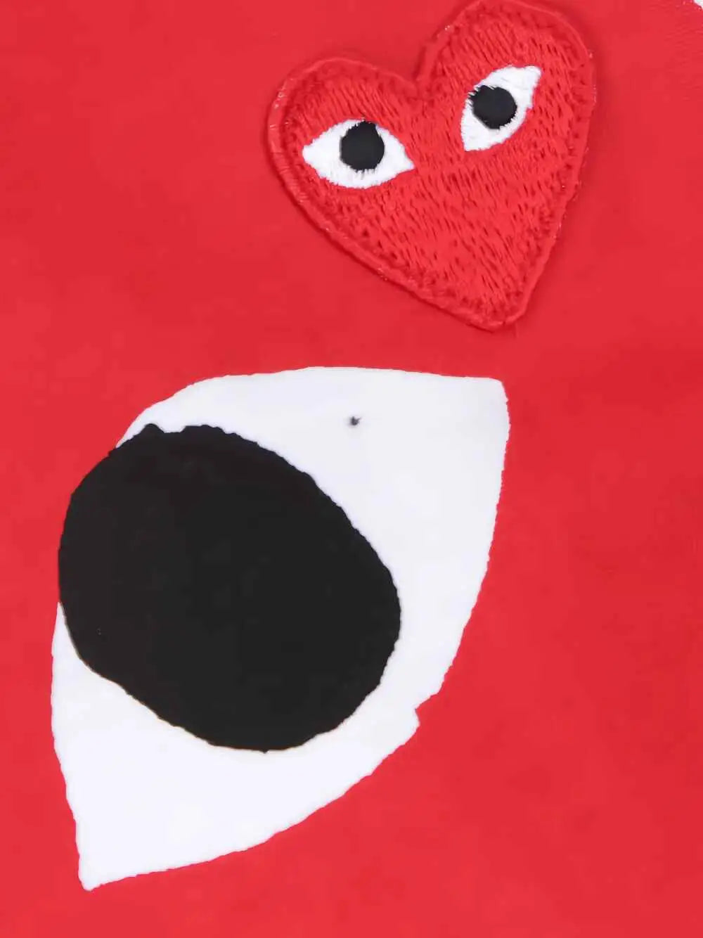 Women’s cdg play white tee with big red heart embroidered eyes patch on red fabric background