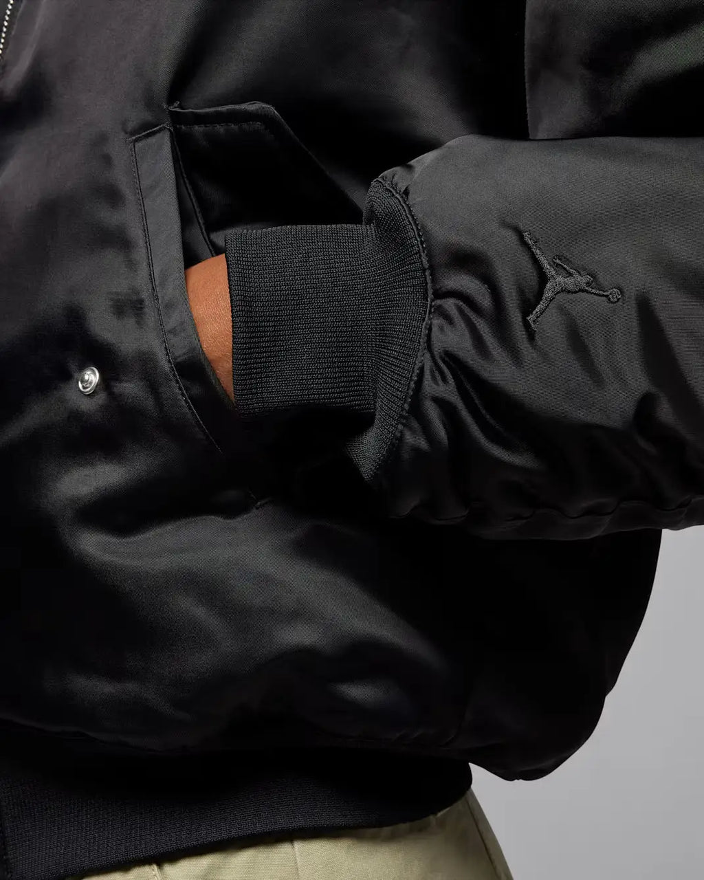 Women’s Jordan Flight Renegade black satin bomber jacket with subtle sheen embroidered jumpman logo on sleeve and ribbed cuffs